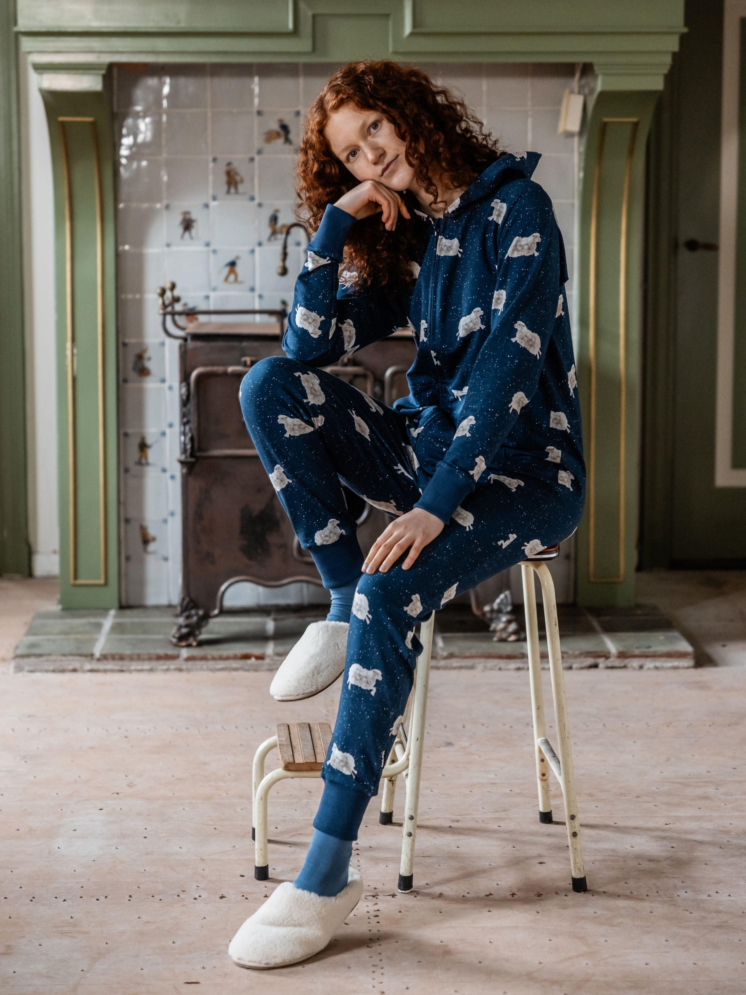 Women wearing a blue onesie with sheep pattern sitting on a stool