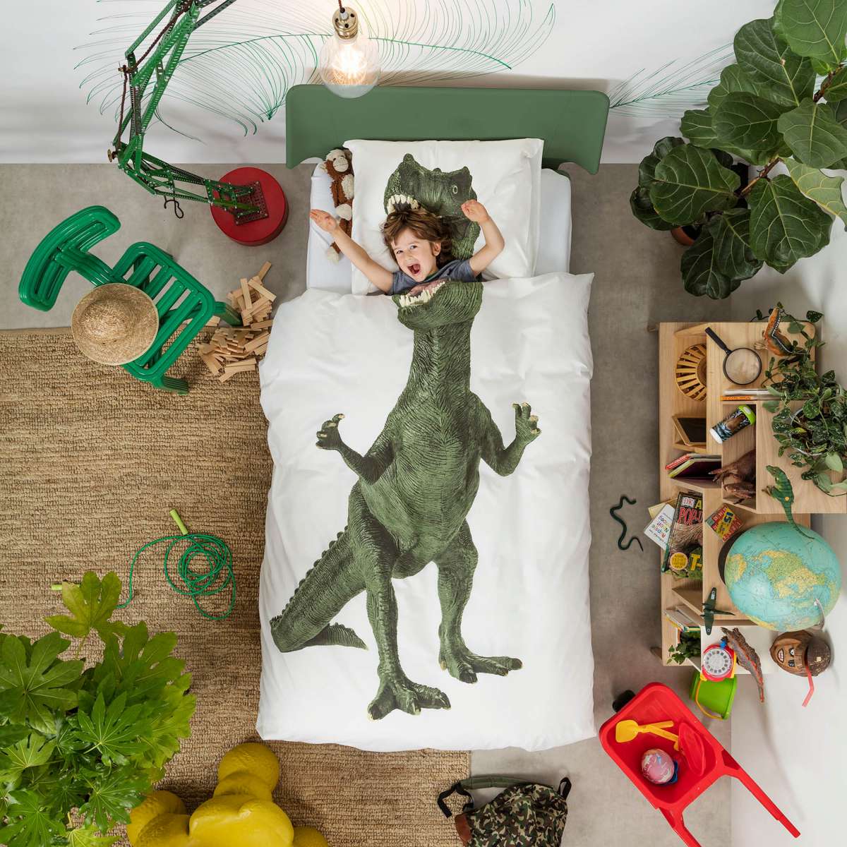 Happy kid underneath a SNURK dinosaur printed duvet cover